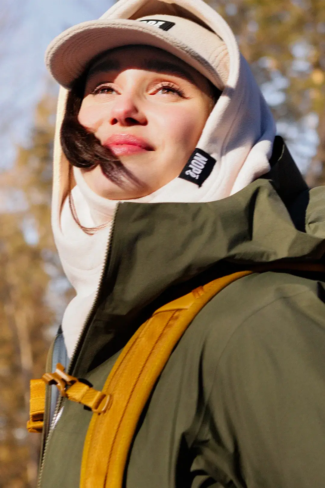 femme en randonnée automnale portant une capuche et une casquette nopé couleur crème