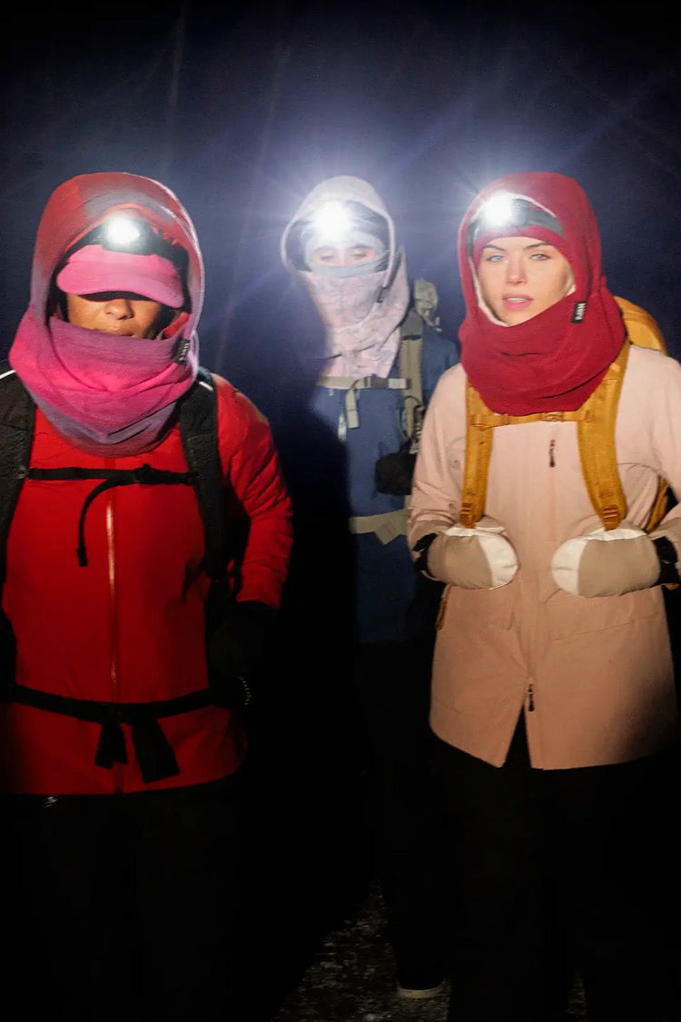 trois femmes en randonnée hivernal le soir portant les capuches nopé