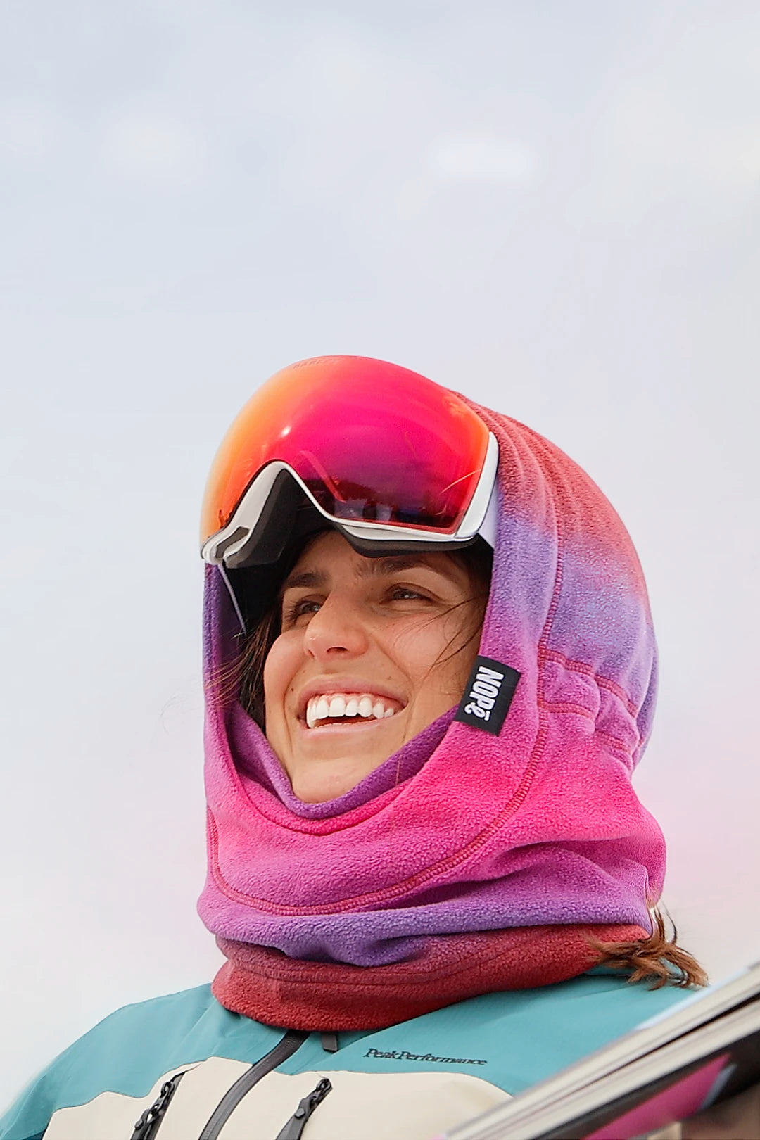 femme en ski portant une surcapuche nopé de couleur aube