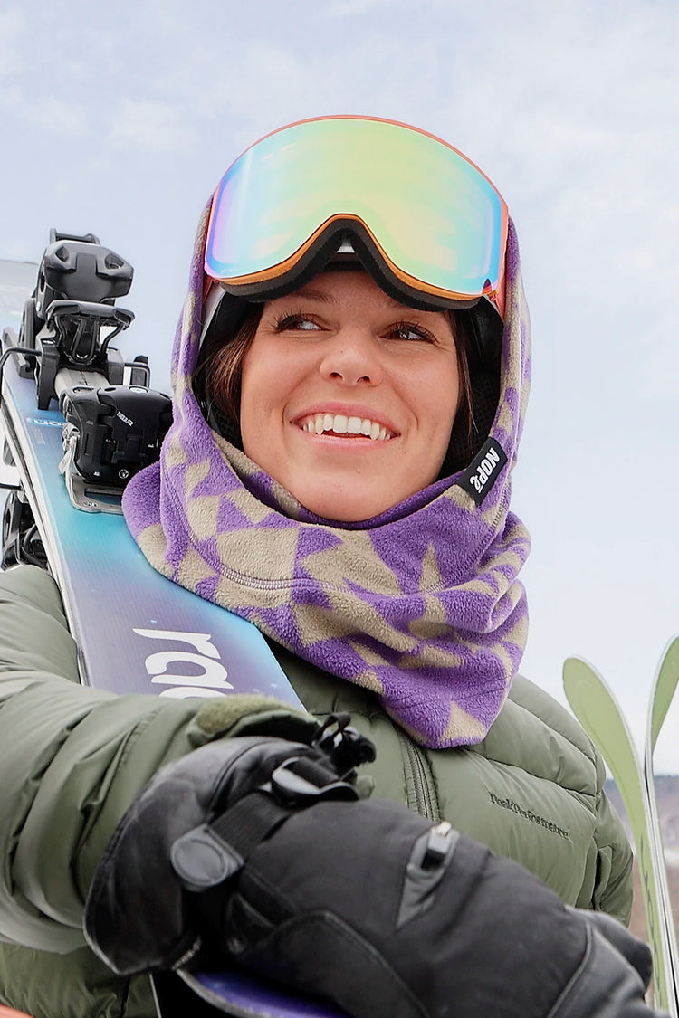 femme tenant ses ski et portant une surcapuche de couleur étoile mauve