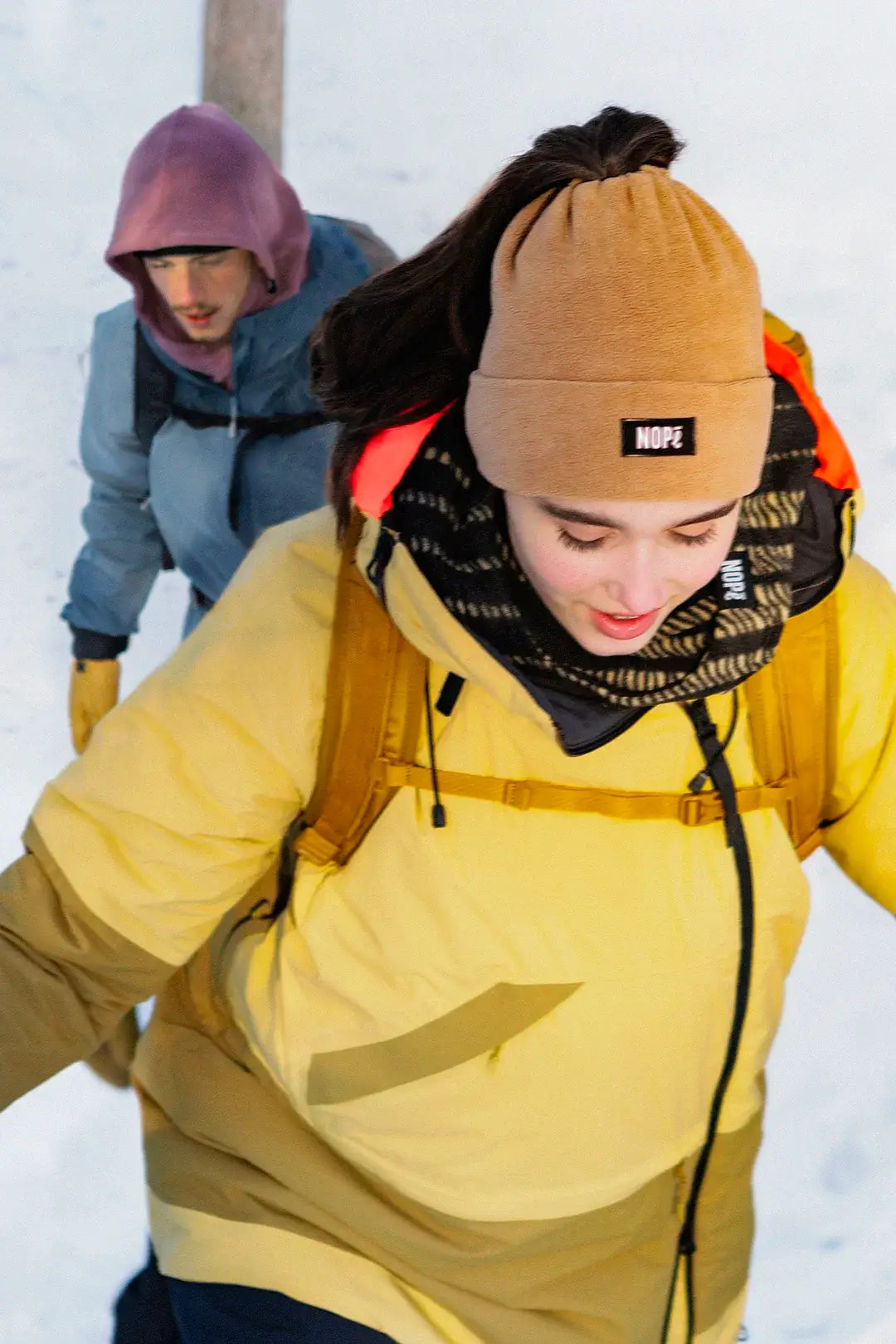 femme et homme en randonnée hivernale portant une tuque convertible nopé et une capuche
